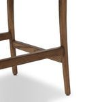 Close-up of footrest and front walnut stool legs with visible wood grain