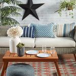 Decorative outdoor sofa with matching pillows in blue and gold tribal patterns and wood coffee table with plants