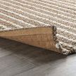 Corner of rug lifted to reveal natural jute backing and sturdy handwoven construction
