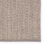 Detailed close-up of rug edges highlighting striped woven pattern in taupe and cream tones