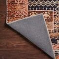 Layla Rug corner lifted to reveal gray non-slip backing on wooden floor surface