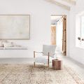 The rug displayed in a bright modern room with chair and wooden side table on top