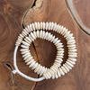 Coiled bone disk beads on wooden surface highlighting creamy color and carved texture of beads