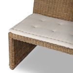 Close-up of rattan weave on backrest meeting the beige fabric cushion on seat