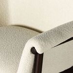 Macro shot of the armrest upholstery revealing boucle fabric grain and dark wood joint