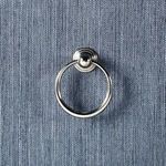 Detailed view of single silver ring drawer pull on textured blue surface