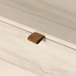 Close-up of toffee-colored leather pull tab against light wood lid