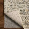 Corner of rug flipped up to reveal natural fiber backing and thin protective rug pad underneath