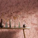 Wallpaper installed on wall behind wooden table with dried flowers in glass and metal vases