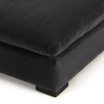 Close-up view of sofa seat cushion corner and lower frame with dark block feet