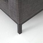 Close-up of black iron base leg with angled corner on dark gray fabric upholstery