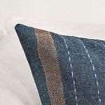 Detail close-up of blue patchwork pillow corner on white chair, highlighting fabric texture