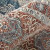 Folded edge highlighting rug's textured, space-dyed polyester pile with rust and blue motifs