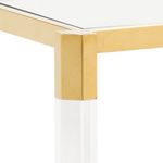 Close-up of gold stainless steel corner joint connecting acrylic legs and glass top of the bar cart