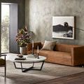 rug styled in living room with brown sofa, marble coffee table, and modern floor lamp on wood floor