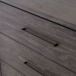 Close-up of drawer handles revealing dark metal hardware and subtle wood grain beneath
