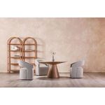 Three Barrow chairs arranged around a round wooden dining table with decorative shelving in background