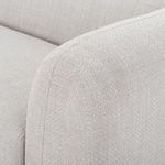 Close-up of armrest seam stitching and rounded contour on light beige fabric upholstery