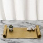Serving scroll tray styled as a centerpiece on marble surface with small plant and decorative stones