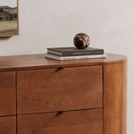 Right side close-up showing rounded edge with black drawer pull and books with marble sphere on top