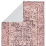 Back side of the rug showing the white backing and reversed pattern in pink and dark purple shades