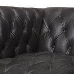 Close-up of tufted ebony leather upholstery showing detailed button stitching and texture