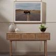 Wooden console table with decorative vases below framed buffalo photograph above rug