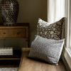 Pillow styled on wooden bench with natural light beside vintage lamp and window curtain