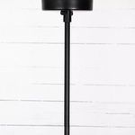 Vertical matte black suspension rod and round mounting plate against white wood wall