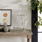Side view of easel on wooden table with framed art and plants in background