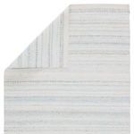Corner view with rug slightly folded to reveal woven underside and reinforced edge binding