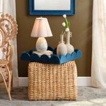 Scalloped linen lamp shade styled on a lit table lamp in a cozy room setting with wicker furniture and decorative vases