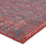 Close-up of corner showing woven texture and stitched red edge of the rug