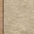 Corner of wool rug on wood floor highlighting high-low pile pattern and muted color variation