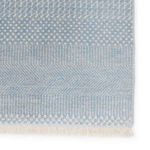 Detail of one corner showing intricate pattern variation and ivory fringe against the blue background
