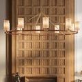 Chandelier lit with tan shades against wood wall paneling and decorative sculpture below