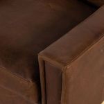 Close-up detail of armrest and seat leather showing fine stitching and natural leather grain.