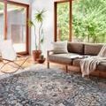 Samra Slate Multi Rug styled in modern living room with large windows, couch, and wood flooring