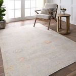 Rug styled in bright room with chair, side table, and wood flooring