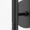 Close-up of matte black metal cylindrical arm and round backplate of wall sconce