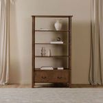 Styled Caroline bookcase in room setting with books and vases on shelves, curtains in background