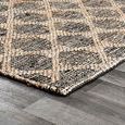 Low angle view of corner edge lying flat on gray wood floor showing rug thickness and edge binding