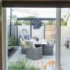 View through sliding glass door to patio with Coronado Dining Chairs arranged around dining table