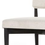 Detailed side view of seat cushion and top of tapered black wood leg with iron tip