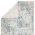 Rug flipped to show solid ivory backing with faint blue pattern visible through the weave