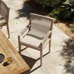Chair set on outdoor patio with sunlight casting partial shadows on cushion and armrests