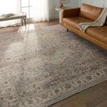 Rug styled in living room setting with leather sofa, sheer curtains, and hardwood flooring