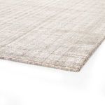 Low angle close-up of rug corner showing finely finished edges and mix of brown and cream fibers
