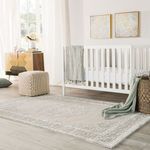 Rug in nursery setting with white crib, pouf, woven basket, and wall art