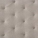 Close-up detail of diamond-tufted grey fabric upholstery on ottoman top